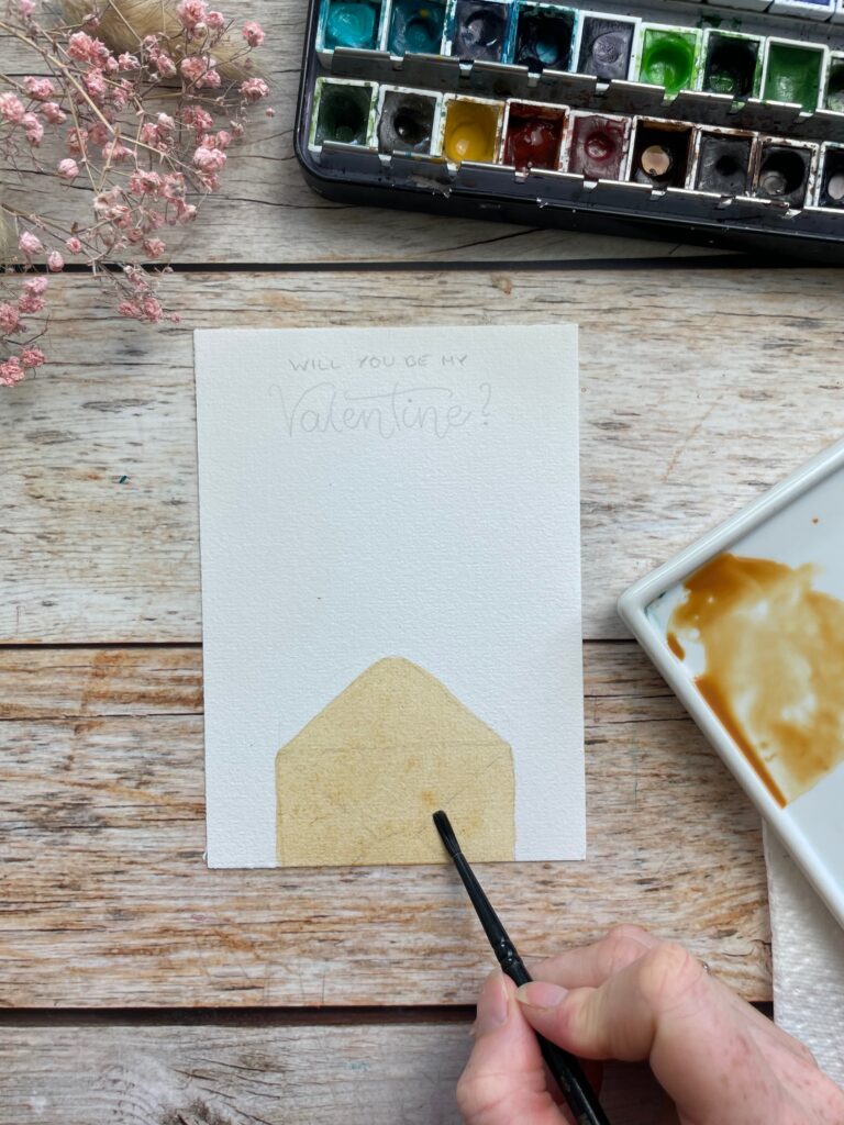 Ein mit hellbrauner Aquarellfarbe grundierter Briefumschlag