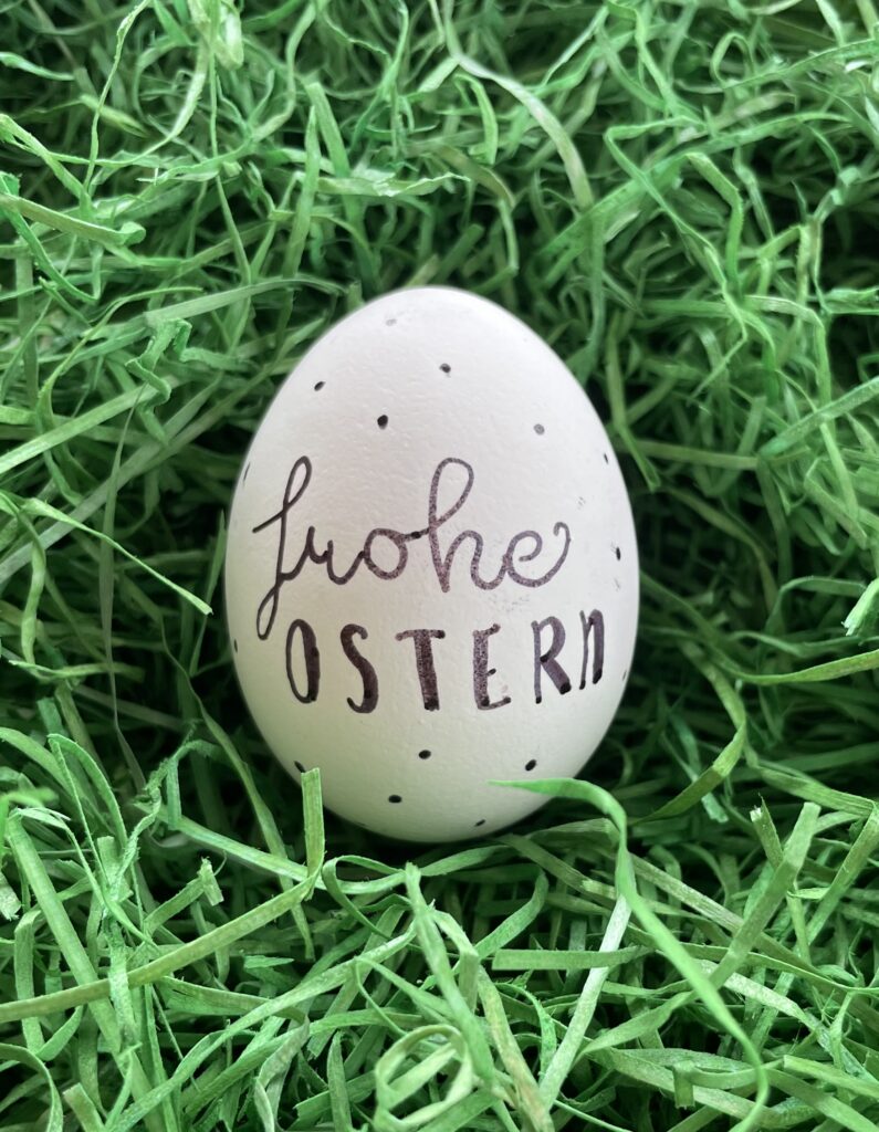 Das Bild zeigt ein Osterei, was mit "Frohe Ostern" beschriftet ist.