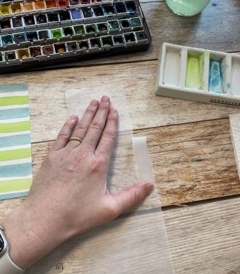 Sandra – Reingemalt – Aquarell malen lernen, einfache Letterings und DIY Grußkarten – Einfache Osterkarte mit Aquarell malen 6 Auf dem Bild wird gezeigt, wie Transparentpapier in die richtige Form vorsichtig abgerissen wird, sodass eine ausgefranste Kante entsteht.