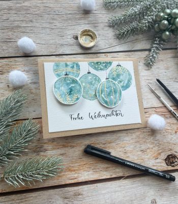 Sandra – Reingemalt – Aquarellmalen lernen, Handlettering und DIY Grußkarten – fünf Inspirationen für einfache DIY Weihnachtskarten 1 Das Bild zeigt eine selbstgemachte Weihnachtskarte mit Aquarell gemalten Christbaumkugeln